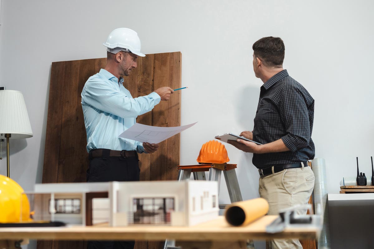 Builder And Client Reviewing House Design Plans